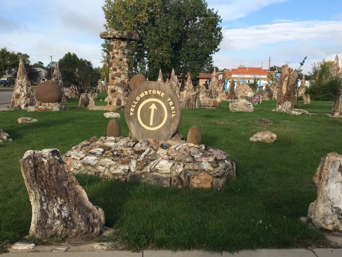 A stone monument with a "Yellowstone Trail" sign surrounded by various rock formations and greenery.