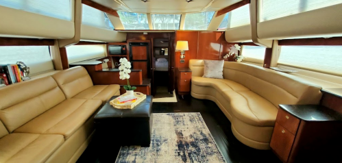 Luxurious yacht interior featuring leather seating, a coffee table, and elegant decor with natural light streaming in.
