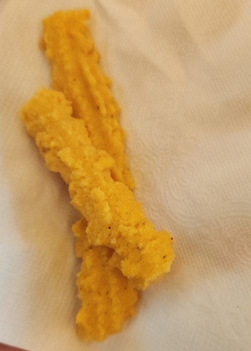 A piece of golden, crispy fried food resting on a white paper towel.