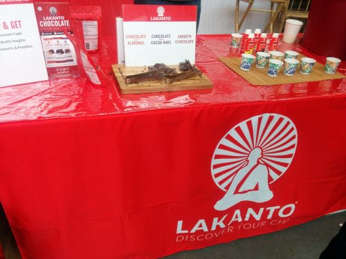 A red table with Lakanto branding, featuring chocolate samples and cups for tasting.