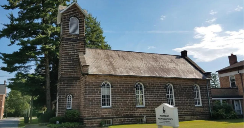 A stone church with a bell tower, surrounded by trees and a sign for Independence Presbyterian Church.