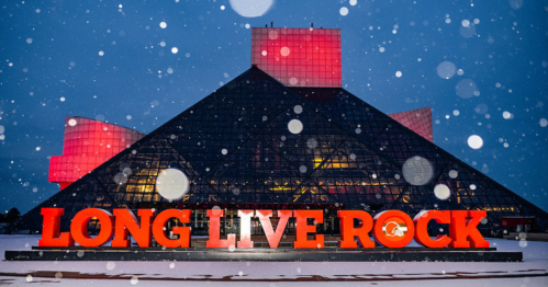 The Rock and Roll Hall of Fame at night, featuring "LONG LIVE ROCK" in bold letters, with snowflakes falling.