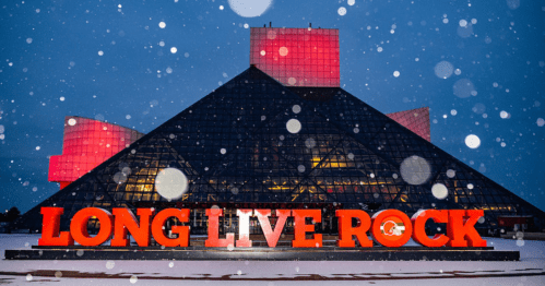 The Rock and Roll Hall of Fame at night, featuring "LONG LIVE ROCK" in bold letters, with snowflakes falling.