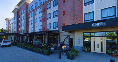 Exterior view of a hotel with a restaurant, featuring outdoor seating and landscaped planters.
