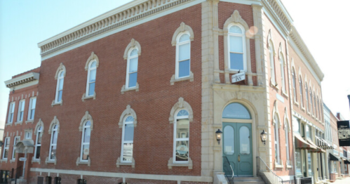 Historic brick building with decorative windows and a central entrance, set against a clear blue sky.