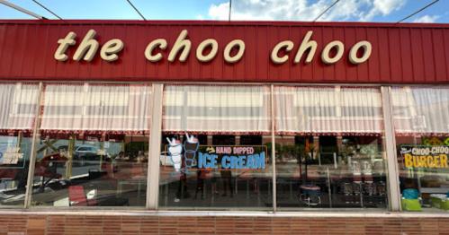 Exterior of "The Choo Choo" restaurant featuring signs for hand-dipped ice cream and burgers, with a bright blue sky above.