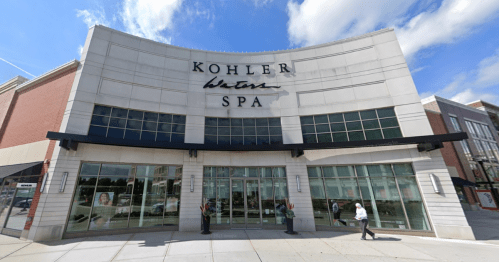 Exterior of Kohler Water Spa, featuring large glass windows and a modern architectural design under a blue sky.