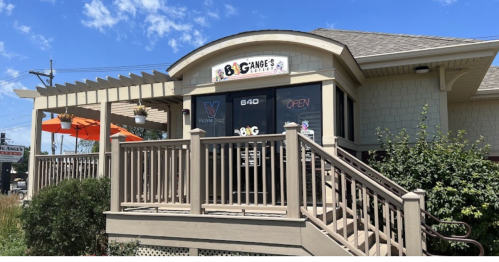 Exterior of Big Change's restaurant with a sign, porch, and orange umbrellas on a sunny day.