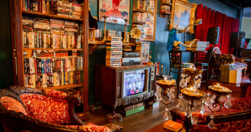 Cozy living room with vintage decor, a TV, a bookshelf filled with DVDs, and ornate furniture.