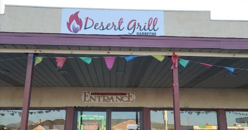 Exterior of Desert Grill Barbecue restaurant with a sign and colorful bunting above the entrance.