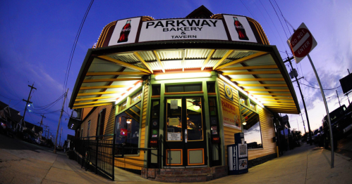 Exterior of Parkway Bakery & Tavern at dusk, featuring bright signage and a welcoming entrance.
