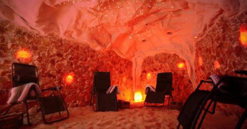 A tranquil salt cave with glowing walls, cozy chairs, and a starry ceiling, creating a relaxing atmosphere.
