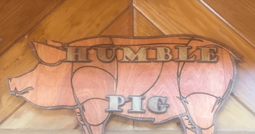 Wooden sign featuring a stylized pig with the words "HUMBLE PIG" carved into it.