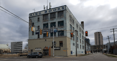 A large, weathered building with "King Books" painted on the side, featuring traffic lights and a cloudy sky.