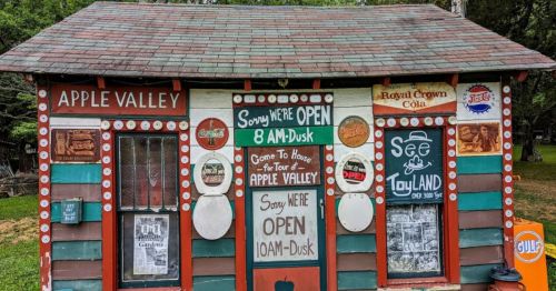 Colorful wooden building with signs indicating it's open for tours, featuring vintage advertisements and playful decorations.