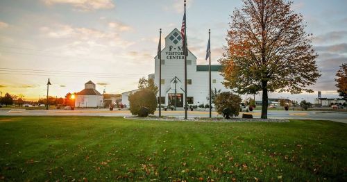 F-M Visitor Center at sunset, featuring flags and autumn foliage in a landscaped area.