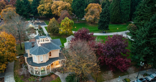Aerial view of a park with colorful autumn trees and a charming house surrounded by greenery.