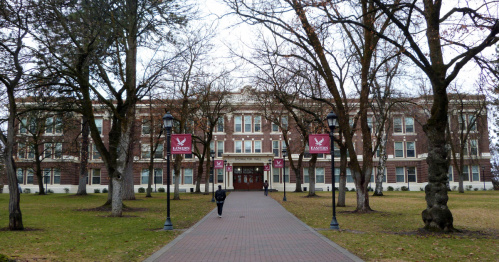 A pathway leads to a large brick building surrounded by bare trees, with banners displaying "Eastern" on either side.