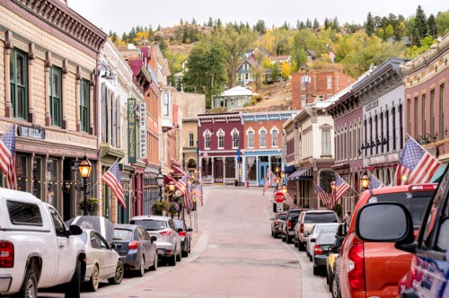 Historic street lined with colorful buildings and American flags, leading up a hill in a quaint town.