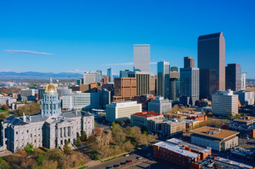 Aerial view of Denver's skyline featuring modern buildings and the historic state capitol with a gold dome.