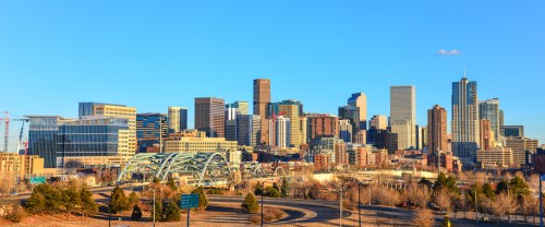 Panoramic view of a city skyline with modern buildings under a clear blue sky.
