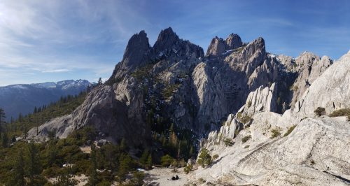 A panoramic view of rugged mountain peaks and rocky terrain under a clear blue sky.