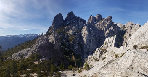 A panoramic view of rugged mountain peaks and rocky terrain under a clear blue sky.
