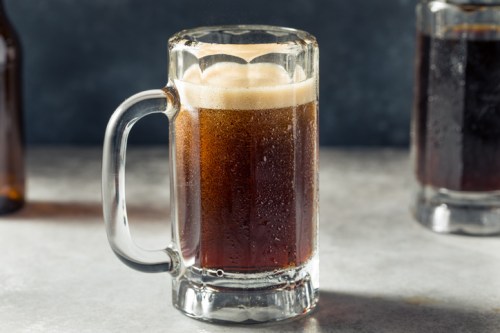 A frosty glass mug filled with dark beer, with bubbles and condensation on the surface.
