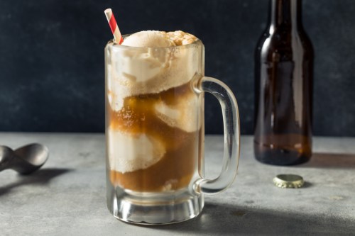 A frosty mug filled with root beer and topped with vanilla ice cream, garnished with a red and white striped straw.