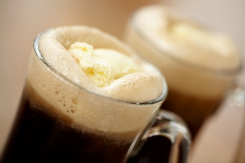 Two frothy mugs of root beer float topped with scoops of vanilla ice cream.