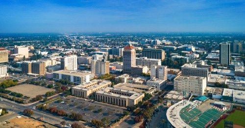 Aerial view of a city skyline featuring tall buildings, clear skies, and a distant horizon.