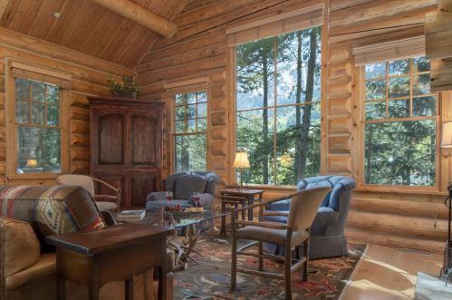 Cozy log cabin interior with large windows, comfortable seating, and a warm, inviting atmosphere.