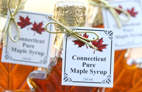 Bottles of Connecticut pure maple syrup with decorative labels and gold bows.