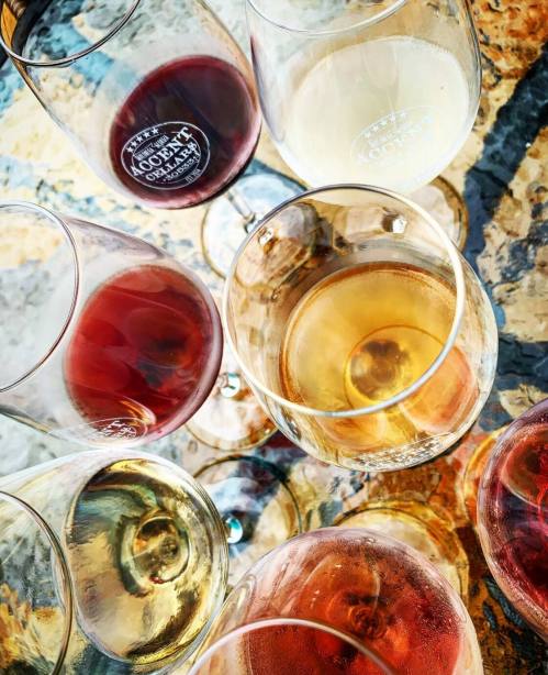 A collection of wine glasses filled with various types of wine, arranged on a textured surface.