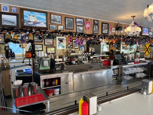 A diner counter decorated with Halloween-themed decor, photos, and condiments, showcasing a nostalgic atmosphere.