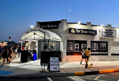 The Stone Pony venue at dusk, with people outside and a clear sky featuring a crescent moon.