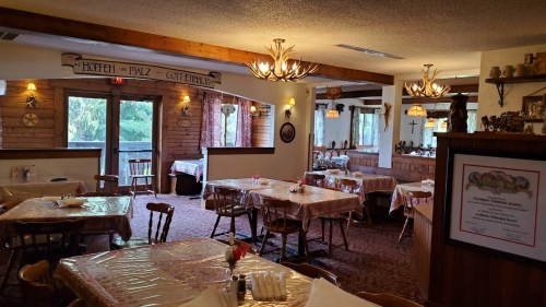 Cozy restaurant interior with wooden decor, tables set for dining, and warm lighting creating a welcoming atmosphere.