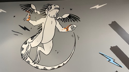 A whimsical mural of a creature with wings and a lizard-like body, holding food and drinks, surrounded by lightning bolts.
