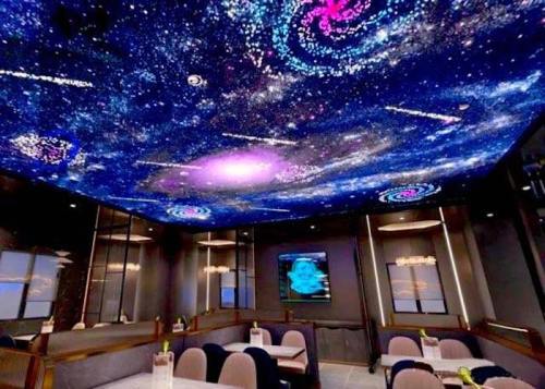 A modern restaurant interior with a galaxy-themed ceiling and elegant seating arrangements.
