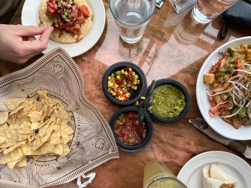 A table with chips, salsa, a taco, and a plate of mixed dishes, alongside glasses of water.
