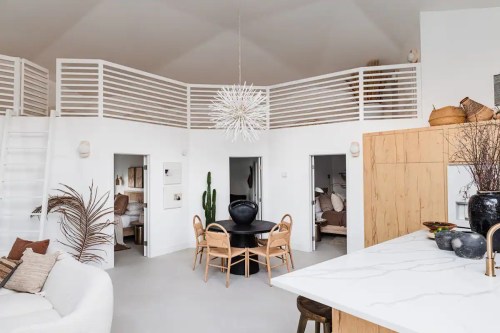 Modern open-concept living space with a round dining table, minimalist decor, and a stylish light fixture.