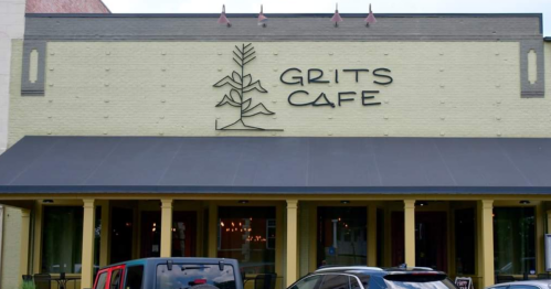 Exterior of Grits Cafe featuring a yellow brick facade, large sign, and outdoor seating area.