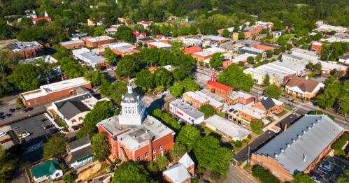 Aerial view of a small town with a mix of buildings, trees, and a prominent courthouse in the foreground.