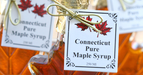 Bottles of Connecticut Pure Maple Syrup with decorative labels and a maple leaf design.