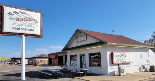Exterior of Smitty's Carry Out, a small restaurant with a sign, picnic tables outside, and a clear blue sky.