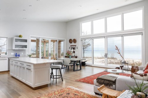Bright, modern living space with large windows, beach view, and stylish furnishings, including a cozy sofa and dining area.
