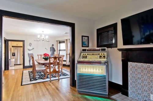 A retro jukebox stands in a cozy living space, with a dining area visible in the background.