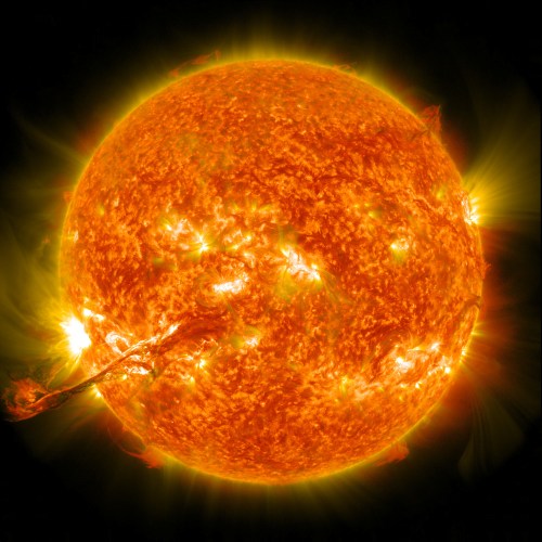 A vibrant, glowing sun with fiery solar flares and a bright, radiant surface against a dark background.