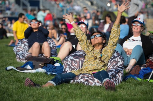 A group of people relax on bean bags outdoors, some wearing 3D glasses, enjoying a sunny event.