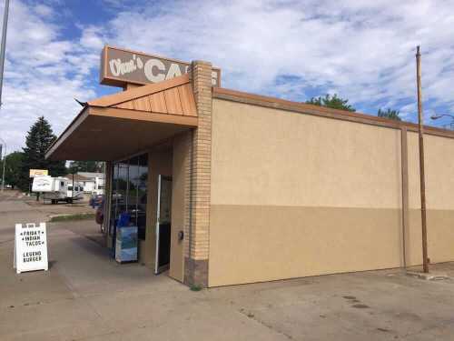 Exterior of a cafe with a sign, featuring a menu board outside and a clear blue sky in the background.